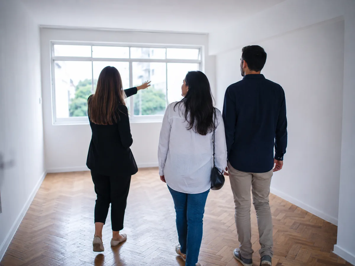 Corretora mostrando um apartamento vazio para um casal durante uma visita